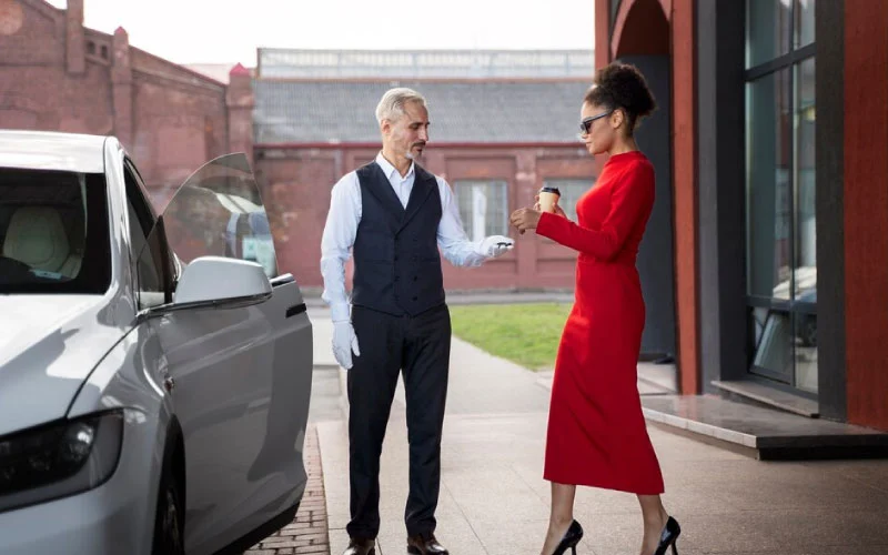 A sleek RideVoova coach parked outside a London corporate event venue with staff disembarking.