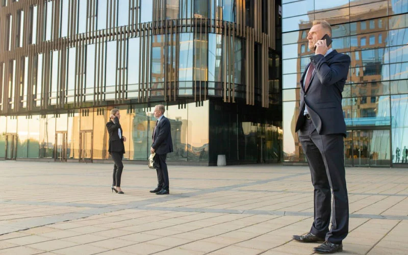 RideVoova branded coach picking up business professionals outside a modern office in London.